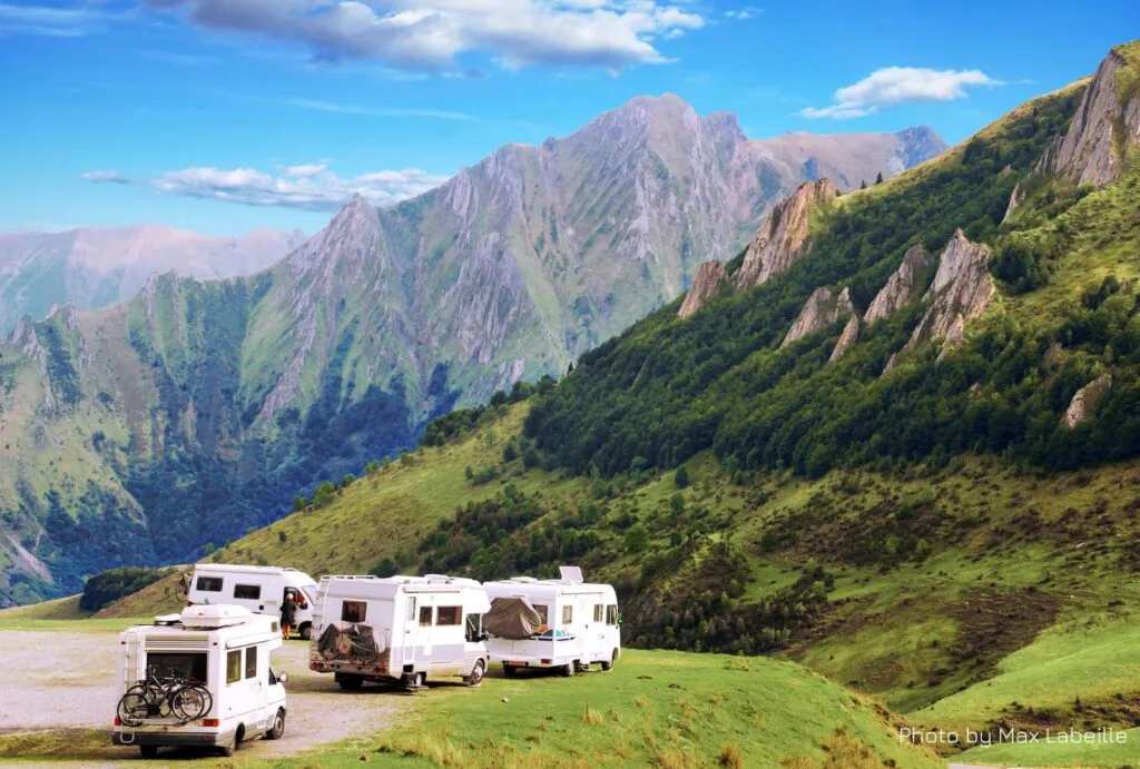 Grupo de autocaravanas estacionadas en un área de descanso rodeada de naturaleza que cuentan con seguro de viajes de autocaravana.