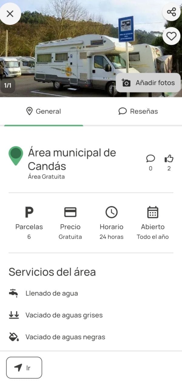 Autocaravanas estacionadas en el área municipal de Candás, con señal visible de zona de servicio y árboles al fondo.
