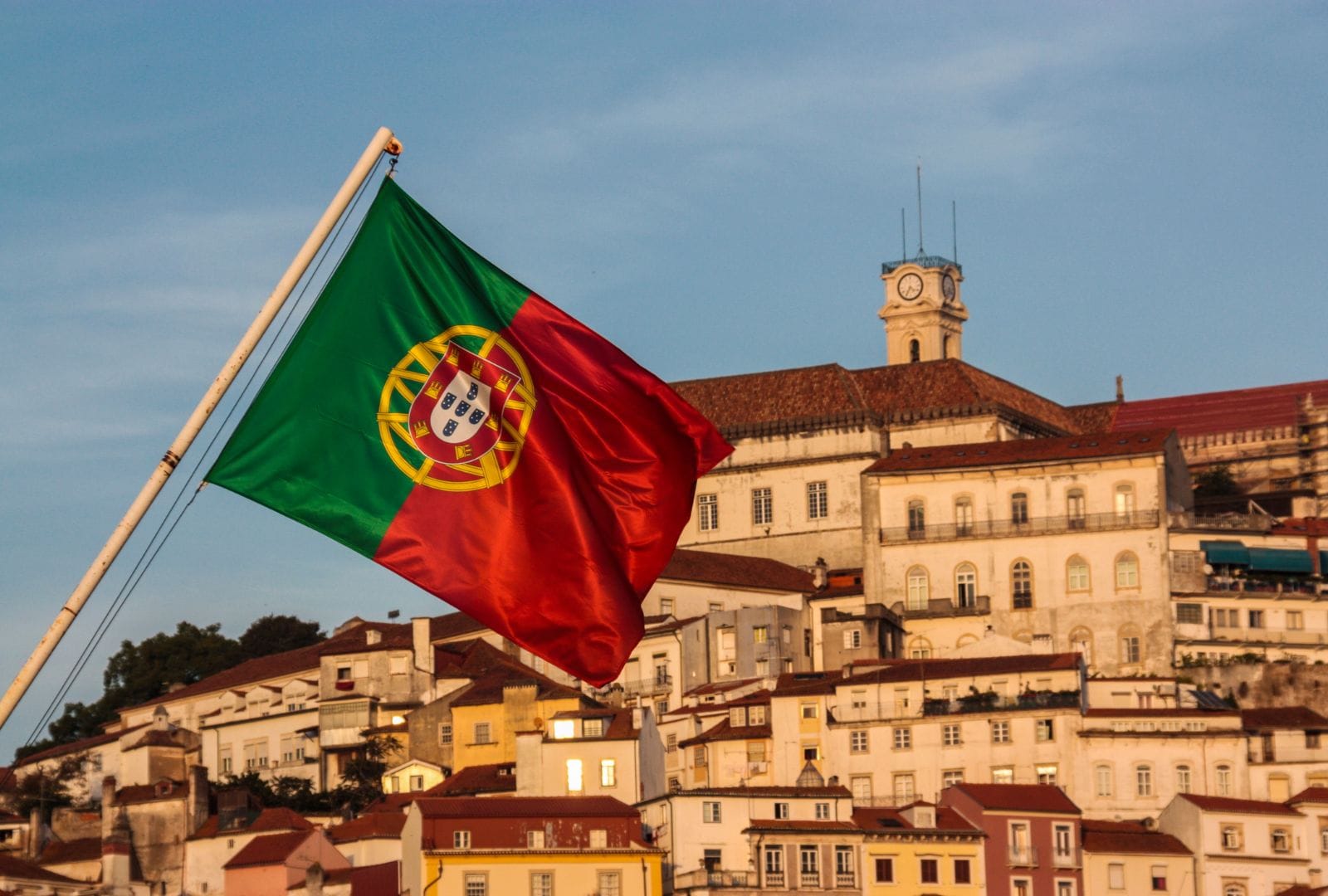 Bandeira-de-Portugal-tremulando-ao-vento-com-a-Universidade-de-Coimbra-ao-fundo.