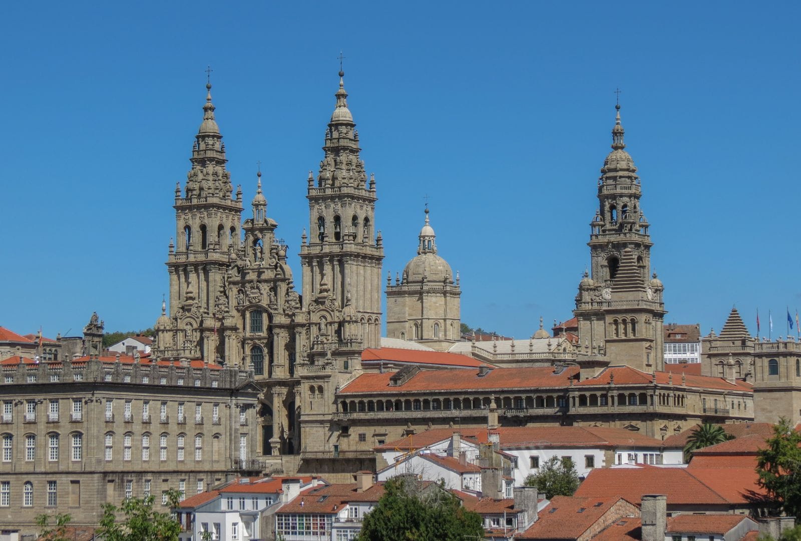 Vista panorámica de la Catedral de Santiago de Compostela con su arquitectura barroca y las torres destacando sobre el cielo azul.