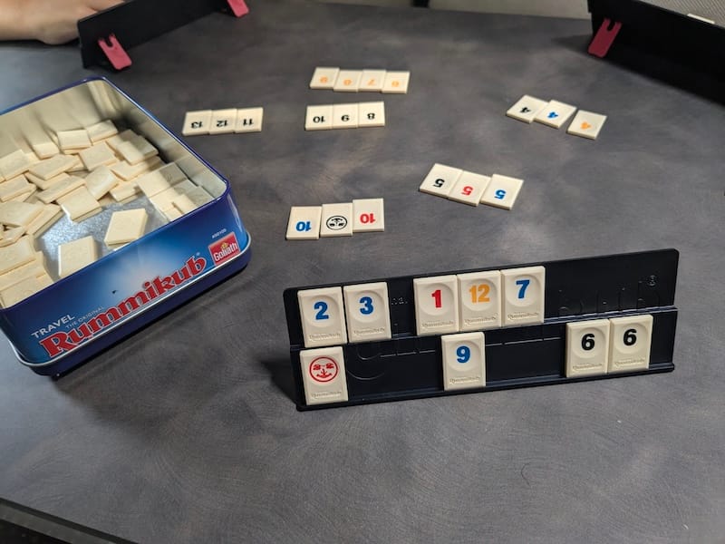 Fichas de Rummikub organizadas por colores en la mesa de madera de una autocaravana.