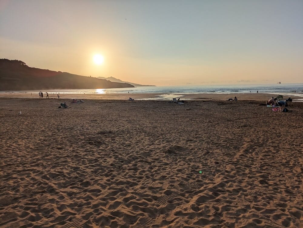 Vista del atardecer taras los acantilados con el gran arenal de la playa de La Arena en primer plano