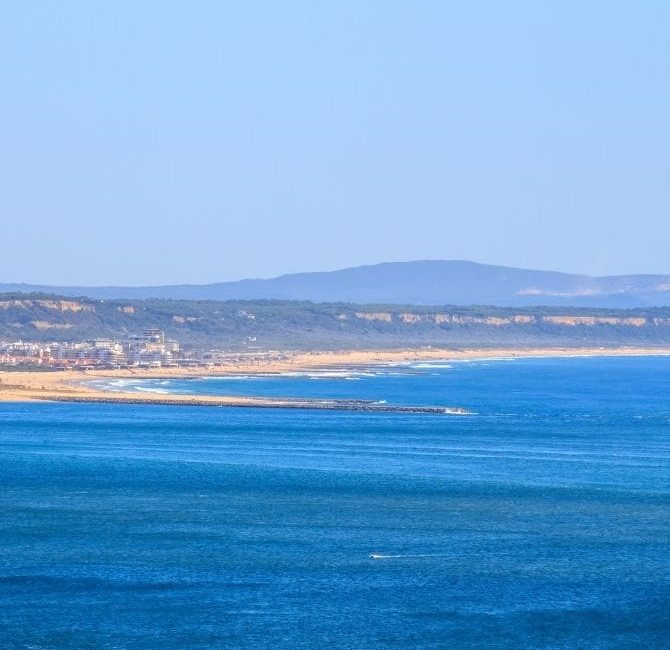 Vista panorámica de la costa de Ericeira, Portugal, con el océano Atlántico y acantilados al fondo.