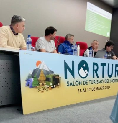 Nortur 2024: Salón de Turismo del Norte – Un evento clave para la industria turística del norte de España Mesa redonda de organizada por TripStop en el evento de turismo Nortur 2024. Al frente, un banner con el logo de Nortur, la frase 'Salón de Turismo del Norte' y las fechas '15 al 17 de marzo 2024'. La imagen muestra a varias personas sentadas en una mesa, con botellas de agua y un ordenador portátil. Al fondo, se proyecta una presentación en una pantalla.